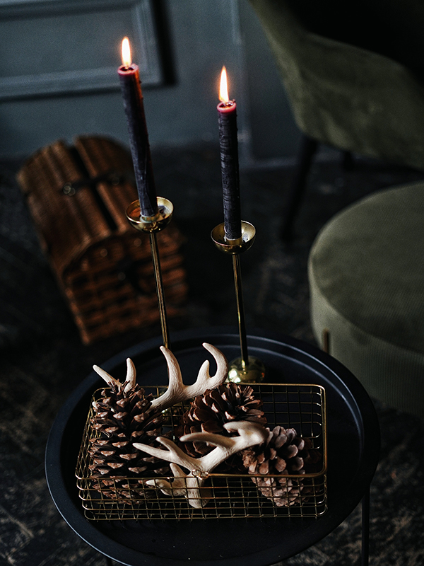 black candles burning on a black plate in a living room with horns underneath